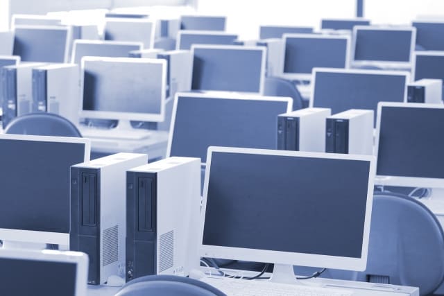 スラッと並んだ電源オフのデスクトップパソコン