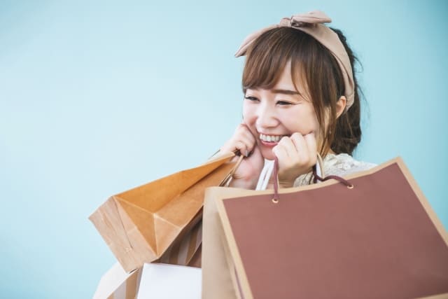 たくさんの紙袋を抱えはにかむ女性